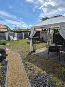 a patio with a white umbrella and some chairs at Dom Gościnny Latarenka in Niechorze