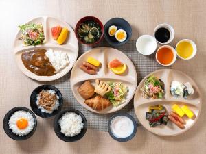 a table with plates of food and bowls of food at Super Hotel Akihabara Suehirocho in Tokyo