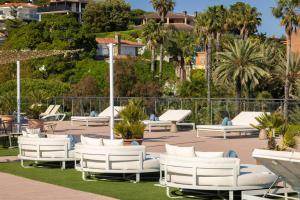 a group of white lounge chairs and palm trees at htop Jadhe SPA 4Sup - Bliss in Calella