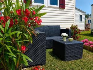 a blue wicker couch and tables in a yard with flowers at Casa Nature's Avlis Bungalow 4XZ in Pataias