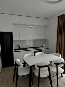 a kitchen with a table and white chairs in it at Lunea Apartment Palm Residence in Vlorë