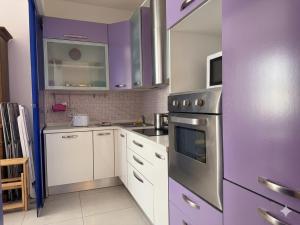 a kitchen with purple cabinets and a stove top oven at Corso79 in Porto Santo Stefano