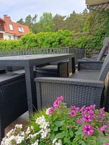 a patio with wicker tables and chairs and flowers at Morski Klimat in Jastrzębia Góra