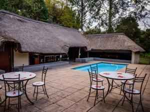 a patio with tables and chairs next to a pool at Pinewood Cottages in Renos
