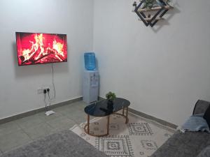 a living room with a table and a tv on the wall at PAZURI - Homes2 in Voi