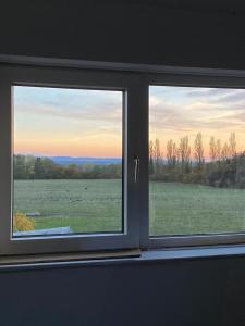 a window with a view of a field with animals at Sunset View - Luxury accommodation in the Cotswolds in Tewkesbury