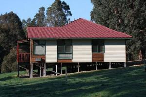 a house with a red roof on a green field at #2 Walpole Wilderness Resort chalet. Spa + forest. in Walpole