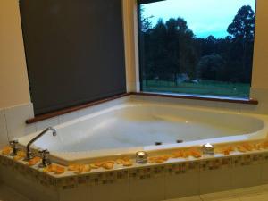 a large bath tub with a window in a bathroom at #2 Walpole Wilderness Resort chalet. Spa + forest. in Walpole