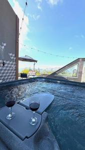 a pool with two glasses of wine in the water at NEVO FAQRA Elevate Your Stay! in Ḩaqlat as Sayyid