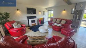 a living room with red leather furniture and a fireplace at Karadow in Saint Just in Roseland