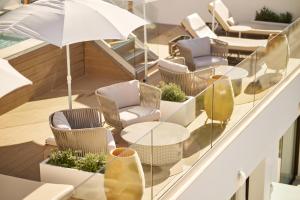 a balcony with chairs and tables and an umbrella at AluaSoul Palma Hotel Adults Only in Can Pastilla