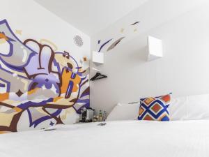 ein Schlafzimmer mit einem Bett und einem Gemälde an der Wand in der Unterkunft ibis Styles Lausanne Center MadHouse in Lausanne