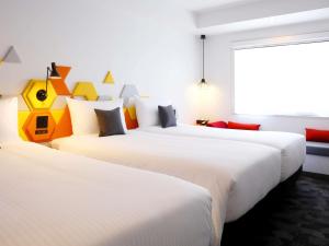 a hotel room with three beds and a window at ibis Styles Tokyo Bay in Urayasu