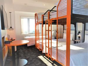 a dorm room with bunk beds and a table and a bed at ibis Styles Tokyo Bay in Urayasu