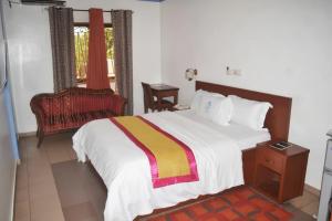 a bedroom with a large bed and a chair at Arenah hotel in Yaoundé