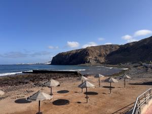 a group of umbrellas on a beach with the ocean at Alquilaencanarias El Palm Mar in Palm-Mar