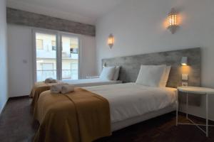 a bedroom with two beds and a large window at 1D Albufeiras Baysight flat in Albufeira