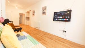 a living room with a tv hanging on a wall at Phlox Garden in Sutton