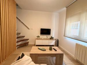 a living room with a table and a tv on a wall at Casa Caracol in Cambados +18 photos