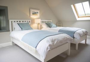 a bedroom with two beds with blue pillows at Riverside Cottage in Comrie