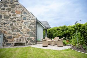 a patio with a table and chairs in front of a stone building at Riverside Cottage in Comrie