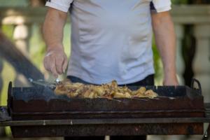 a man is cooking food on a grill at Gora Babilina in Gordi