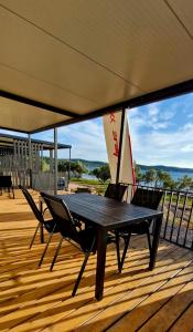 a table and two chairs on a deck with a boat at Mobile Homes Gasperino in Pirovac