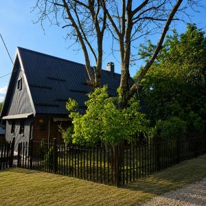 a barn with a black roof behind a fence at Country house in nature -10 min from Nikola Tesla Memorial Center-peace and privacy in Klanac