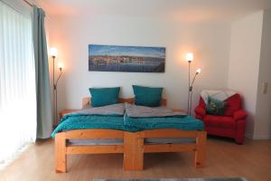 a bedroom with a bed and a red chair at Apartment "An der Süderschmiede" in Sieverstedt