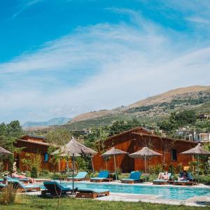 a pool with chairs and umbrellas next to a resort at Mesopotam Agrotourism Resort in Sarandë