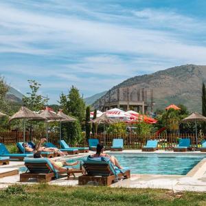 two people laying on lounge chairs by a swimming pool at Mesopotam Agrotourism Resort in Sarandë