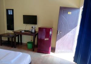 a room with a pink refrigerator and a desk and a television at Sabbia Rossa Beach Resort in Arambol