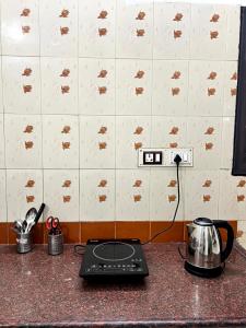 a kitchen counter with a stove and a tea kettle at SK Aarshan's Homestay in Tiruchirappalli