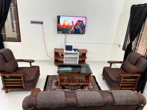 a living room with a couch and two chairs and a tv at SK Aarshan's Homestay in Tiruchirappalli