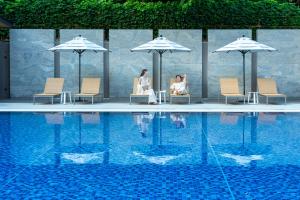 two people sitting under umbrellas next to a swimming pool at Okinawa Harborview Hotel in Naha