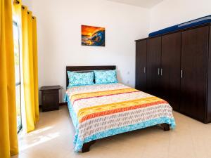 a bedroom with a bed with a wooden cabinet and yellow curtains at Solrise Villa in Palmar +18 photos