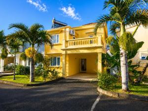 a yellow house with palm trees in front of it at Solrise Villa in Palmar