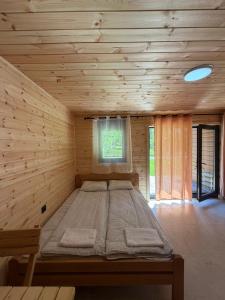 a large bed in a wooden room with a window at Riverside - Mountain Stay with Sauna in Vusanje