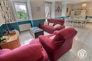 a living room with two red chairs and a table at Les cerisiers in Hinlé +26 photos