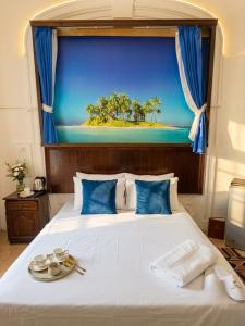 a bedroom with a large bed with a painting of a beach at Acropole Alexandria Hotel in Alexandria