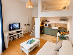 a living room with a white couch and a kitchen at " Studio Vasconia " Hyper Centre - Mezzanine -Wifi in Muret