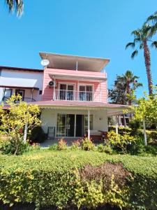 a pink house with palm trees and bushes at Palladium Villa in Side