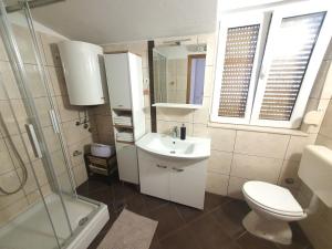 a bathroom with a sink and a toilet and a shower at Apartments Jelica in Slatine +42 photos