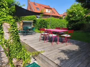 a wooden deck with a red table and chairs at K94 Fischerhaus in Greetsiel