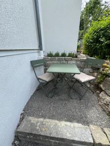 a green table and two chairs next to a wall at Casa Souterrain in Immenstaad am Bodensee