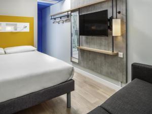 a bedroom with two beds and a flat screen tv at ibis budget Swindon Town Centre in Swindon