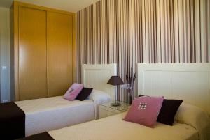 a hotel room with two beds with pink pillows at APARTAMENTOS DE CANELAS SUITES con AMPLIAS TERRAZAS in Portonovo