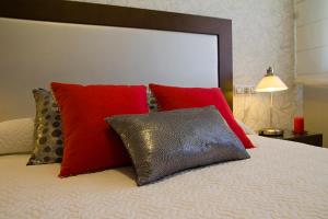 un letto con cuscini rossi e rossi sopra di APARTAMENTOS DE CANELAS SUITES con AMPLIAS TERRAZAS a Portonovo