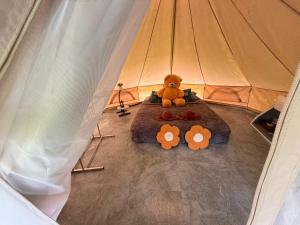a teddy bear sitting on a bed in a tent at Amornkeeree Khao Sok Camping in Khao Sok National Park