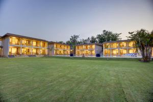a large building with a grass field in front of it at Cygnett Collection in Jim Corbett